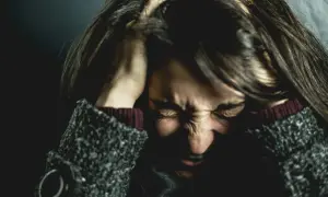 Femme se tenant la tête, visage crispé par la douleur, évoquant la souffrance de l'endométriose et de la migraine.
