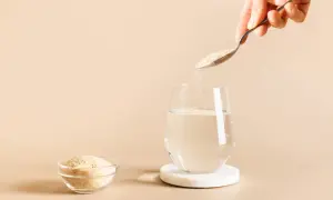 Une cuillère verse du psyllium, une poudre naturelle, dans un verre d'eau. C'est quoi le psyllium ? Une fibre soluble bénéfique.