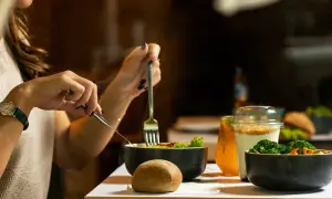Une femme mange une salade et des légumes, un repas sain pour savoir à quoi sert la vitamine B12.