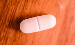 Comprimé blanc sur fond orangé. Une pilule de magnésium marin, attention aux effets secondaires.