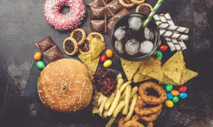 Un assortiment de 9 aliments mauvais pour les yeux : beignets, chocolat, tartes, nachos, soda, frites, oignons frits, bonbons et un hamburger.