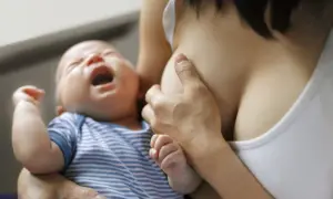 Bébé pleure pendant l'allaitement. Une mère tient son enfant, possiblement pour soulager des symptômes de mastite.