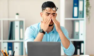 Homme fatigué au bureau, se frottant les yeux devant son ordinateur. Que faire contre la fatigue ?