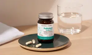 Bouteille de probiotiques Aroma-Zone sur une assiette, avec des gélules et un verre d'eau. Idéal pour savoir quand faire une cure de probiotiques.