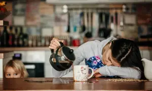 Une femme, accablée par une grosse fatigue soudaine, essaie de se servir un café. Un enfant la regarde, perplexe.