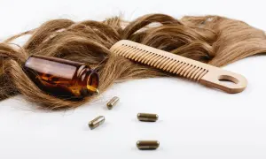 Chevelure brune, peigne en bois et pilules de biotine. Découvrez les biotine bienfaits pour des cheveux forts et brillants.