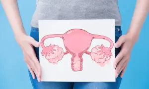 Une femme tient une illustration d'organes reproducteurs féminins, symbolisant peut-être une mycose ou des douleurs aux ovaires.