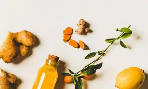 Gingembre, curcuma tranché, citron et une bouteille de liquide doré. Un remède naturel pour la digestion.