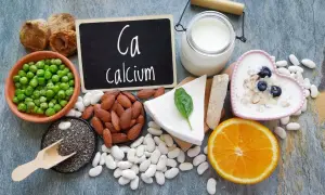 Assortiment d'aliments riches en calcium : lait, yaourt, fromage, amandes, haricots blancs, pois, figues séchées, graines de chia et orange.