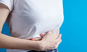 Une femme se tient les mains sur le ventre, ressentant une douleur en haut de l'estomac au milieu.