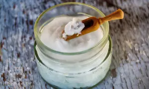 Un pot d'huile de coco avec une petite cuillère en bois. Attention, l'huile de coco danger pour la santé est un sujet de débat.