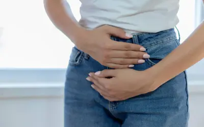 Une femme se tient les mains sur le bas-ventre, l'air préoccupée. Elle pourrait se demander pourquoi j'ai mal au ovaire.