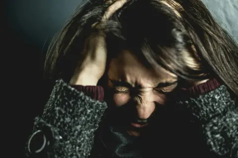 Femme se tenant la tête, visage crispé par la douleur, évoquant la souffrance de l'endométriose et de la migraine.