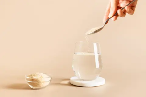 Une cuillère verse du psyllium, une poudre naturelle, dans un verre d'eau. C'est quoi le psyllium ? Une fibre soluble bénéfique.