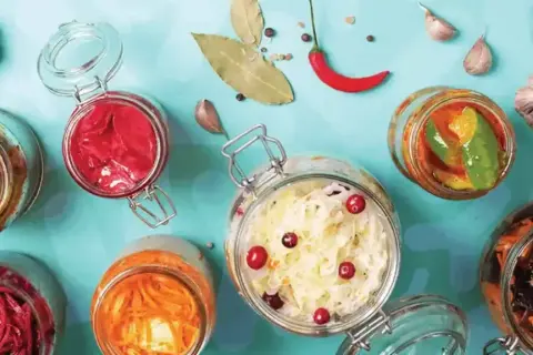 Bocaux de légumes fermentés, un aliment probiotique savoureux et coloré, avec ail, piment et feuilles de laurier.