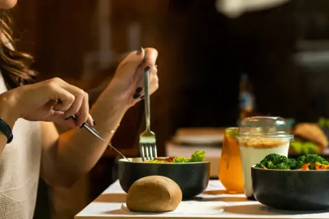 Une femme mange une salade et des légumes, un repas sain pour savoir à quoi sert la vitamine B12.