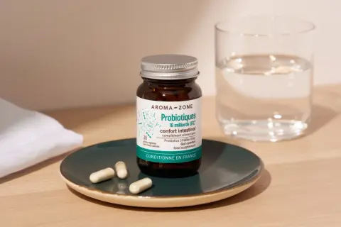 Bouteille de probiotiques Aroma-Zone sur une assiette, avec des gélules et un verre d'eau. Idéal pour savoir quand faire une cure de probiotiques.