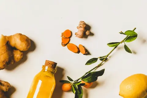 Gingembre, curcuma tranché, citron et une bouteille de liquide doré. Un remède naturel pour la digestion.
