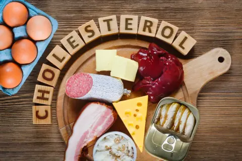 Œufs, beurre, foie, saucisson, lard, fromage, sardines en conserve et dés en bois formant le mot "cholestérol". Ces aliments sont riches en graisse saturée.