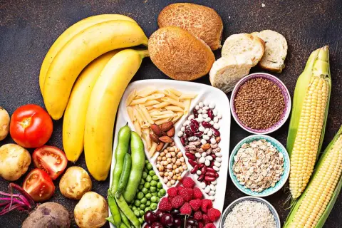 Bananes, pains, pâtes, maïs, riz, avoine, haricots, pois, baies et fruits : un assortiment coloré d'aliments riches en glucides.