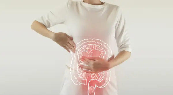 Une femme tient son abdomen, où une illustration des intestins est superposée, suggérant des problèmes intestinaux.