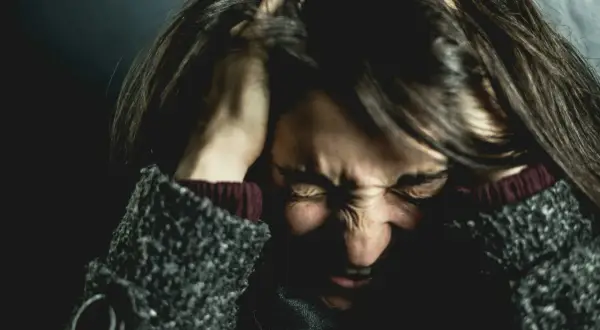 Femme se tenant la tête, visage crispé par la douleur, évoquant la souffrance de l'endométriose et de la migraine.