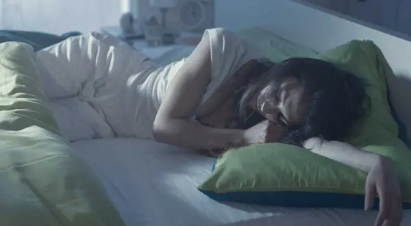 Une femme dort paisiblement, cherchant des solutions pour comment éviter les bouffées de chaleur la nuit.
