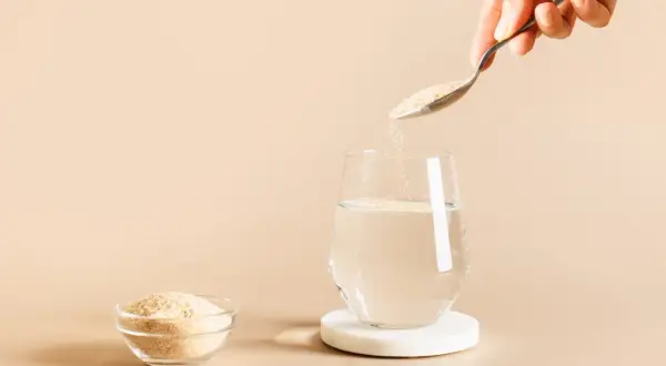 Une cuillère verse du psyllium, une poudre naturelle, dans un verre d'eau. C'est quoi le psyllium ? Une fibre soluble bénéfique.