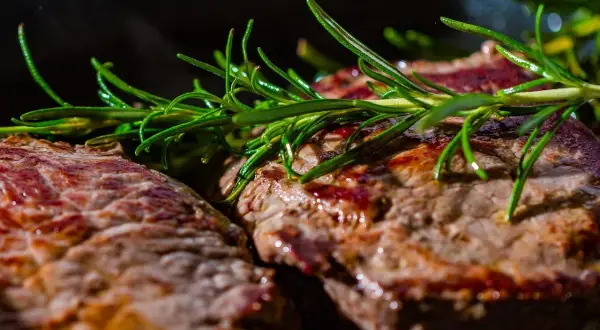 Deux steaks grillés, parsemés de romarin frais. Ces aliments riches en glutamine sont parfaits pour la récupération musculaire.