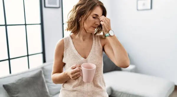Une femme se tient la tête, une tasse à la main, le regard perdu. Que peut cacher une grande fatigue ?