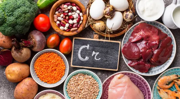 Assiette de foie, poulet, crevettes, œufs, lentilles, haricots, brocolis, tomates, betteraves, pommes de terre, concombre, et un tableau noir avec "Cr" pour les chrome bienfaits.