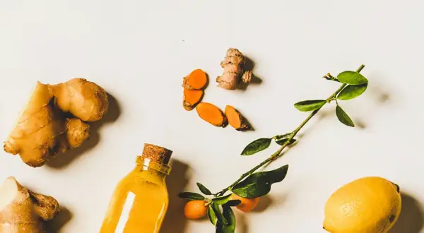 Gingembre, curcuma tranché, citron et une bouteille de liquide doré. Un remède naturel pour la digestion.