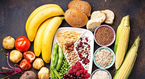 Bananes, pains, pâtes, maïs, riz, avoine, haricots, pois, baies et fruits : un assortiment coloré d'aliments riches en glucides.
