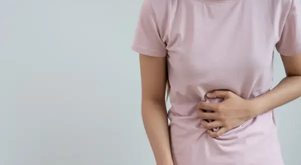 Femme tenant son ventre, souffrant de digestion difficile. Peut-être un remède grand-mère serait utile ?