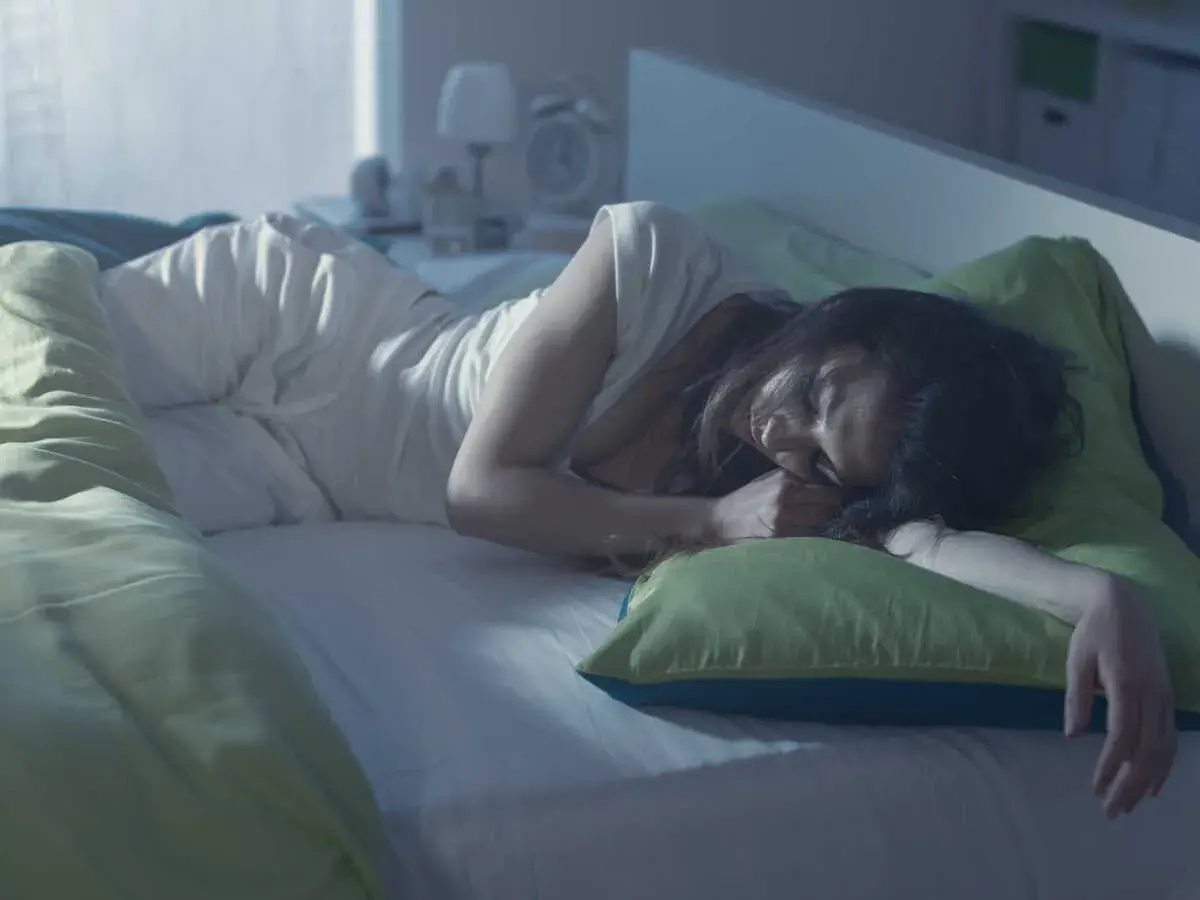 Une femme dort paisiblement, cherchant des solutions pour comment éviter les bouffées de chaleur la nuit.