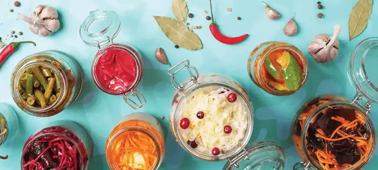 Bocaux de légumes fermentés, un aliment probiotique savoureux et coloré, avec ail, piment et feuilles de laurier.