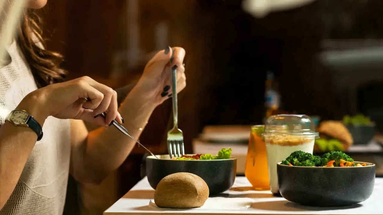 Une femme mange une salade et des légumes, un repas sain pour savoir à quoi sert la vitamine B12.