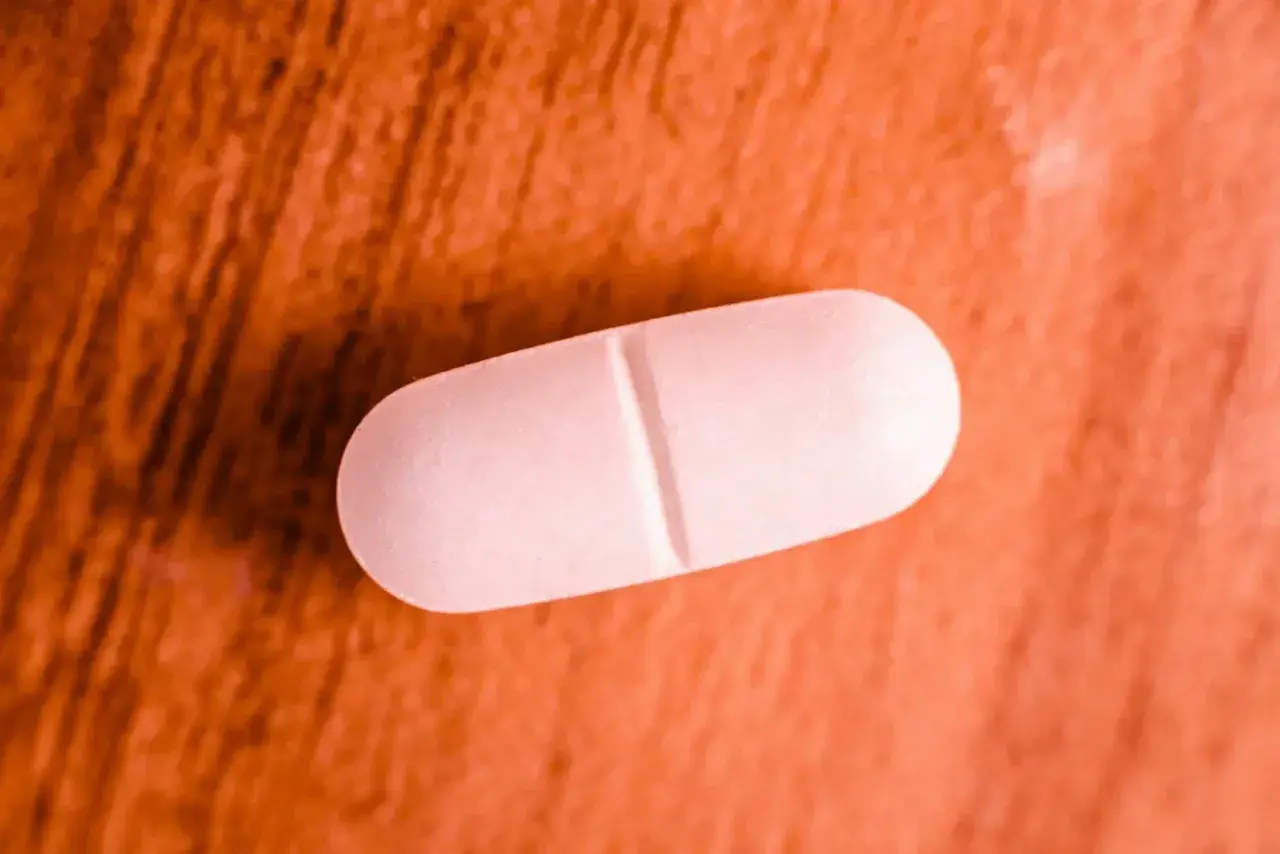 Comprimé blanc sur fond orangé. Une pilule de magnésium marin, attention aux effets secondaires.