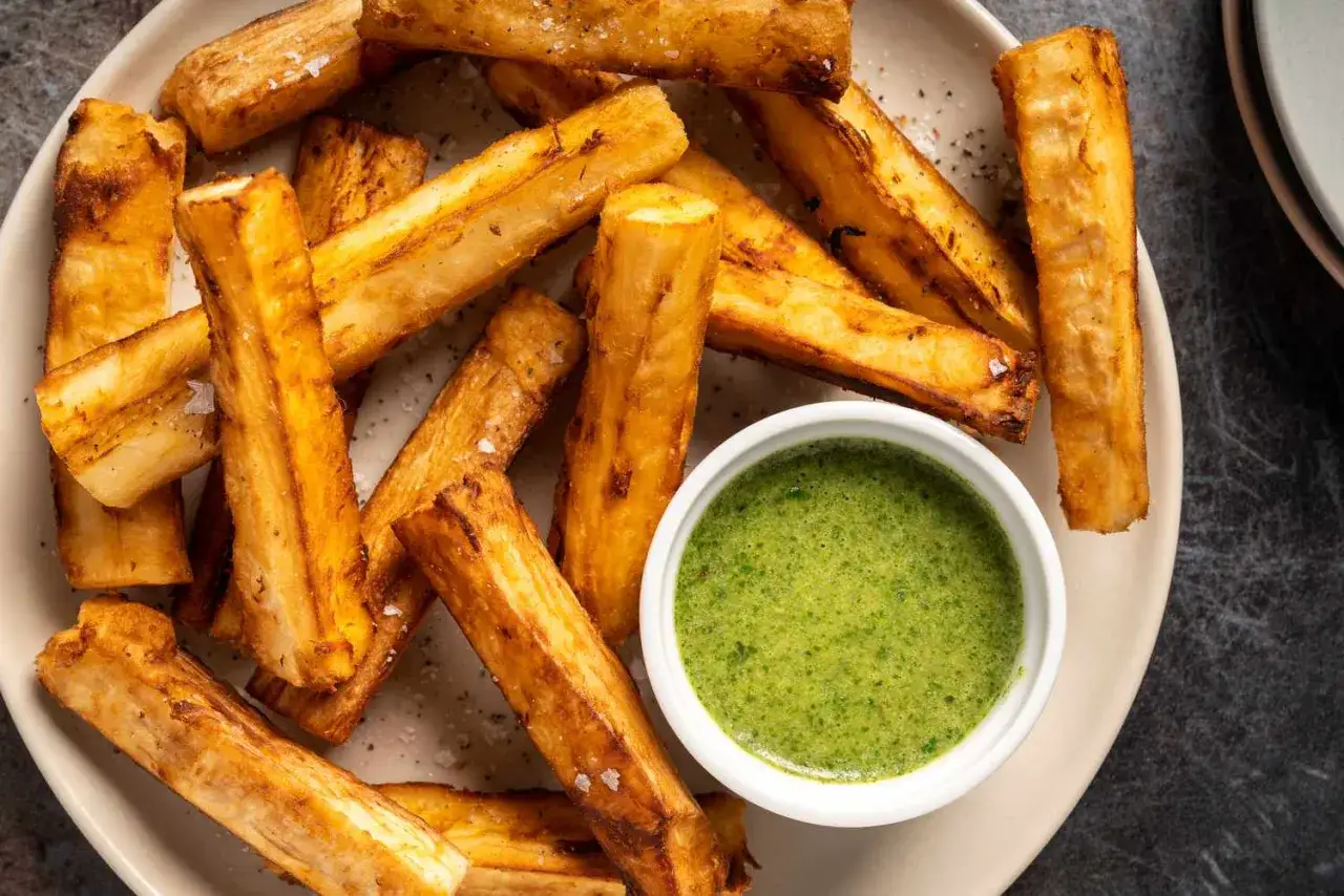 Bâtonnets de manioc dorés et croustillants, accompagnés d'une sauce verte vibrante. Découvrez les manioc bienfaits pour une alimentation saine et savoureuse.