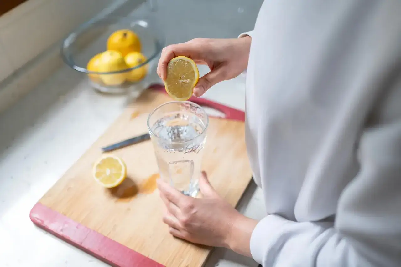 Une main presse un citron dans un verre d'eau, une m&eacute;thode naturelle pour soulager les gaz intestinaux.