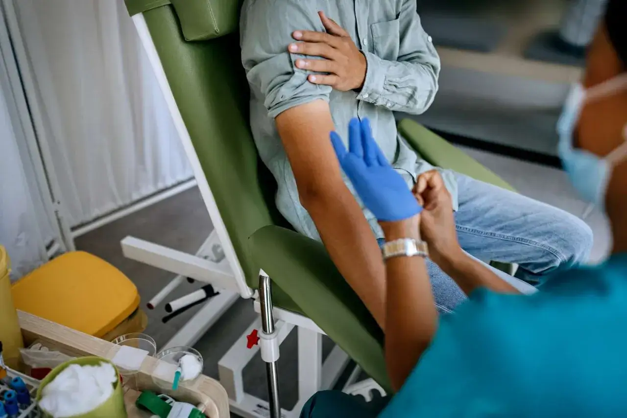 Prélèvement sanguin pour un test de carence en magnésium. Un patient est assis dans un fauteuil médical, son bras tendu.
