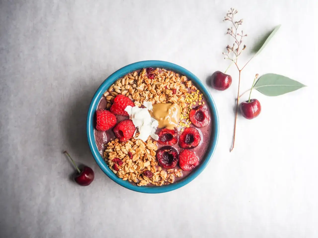 Bol de smoothie aux fruits rouges, granola, beurre de cacahuète et graines de tournesol. Les graines de tournesol bienfaits sont nombreux pour la santé.