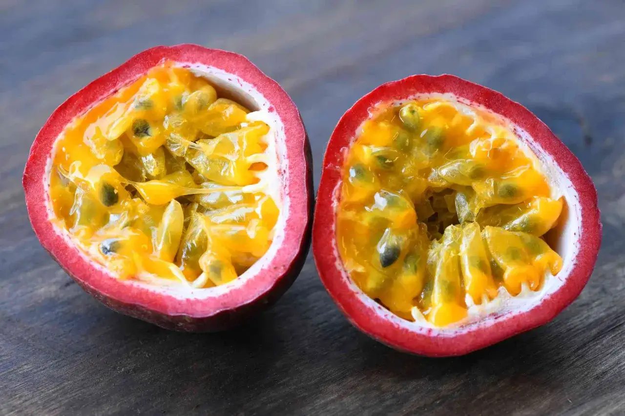 Un fruit de la passion coupé en deux, révélant sa pulpe juteuse et ses graines. Un concentré de saveurs et de fruit de la passion bienfaits.