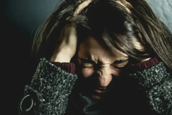 Femme se tenant la tête, visage crispé par la douleur, évoquant la souffrance de l'endométriose et de la migraine.