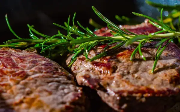 Deux steaks grillés, parsemés de romarin frais. Ces aliments riches en glutamine sont parfaits pour la récupération musculaire.