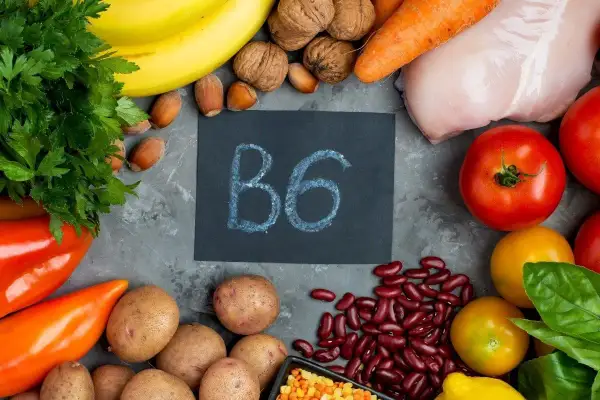 Assortiment d'aliments riches en vitamine B6 : poulet, bananes, pommes de terre, haricots rouges, noix, carottes, poivrons, tomates, persil.