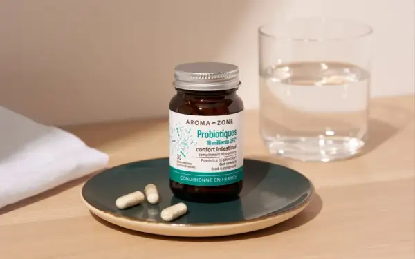 Bouteille de probiotiques Aroma-Zone sur une assiette, avec des gélules et un verre d'eau. Idéal pour savoir quand faire une cure de probiotiques.