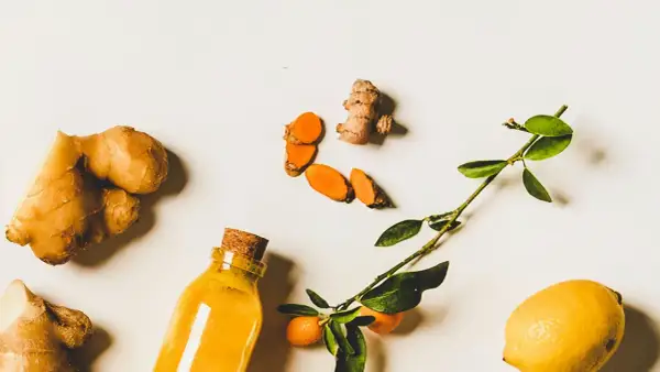 Gingembre, curcuma tranché, citron et une bouteille de liquide doré. Un remède naturel pour la digestion.