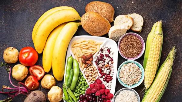 Bananes, pains, pâtes, maïs, riz, avoine, haricots, pois, baies et fruits : un assortiment coloré d'aliments riches en glucides.