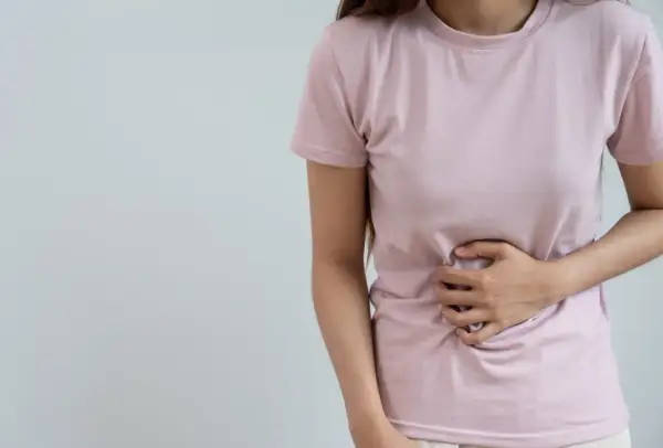 Femme tenant son ventre, souffrant de digestion difficile. Peut-être un remède grand-mère serait utile ?